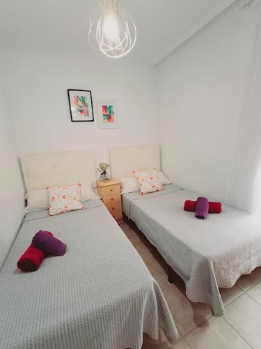 two beds in a room with white walls and purple pillows at Altos del Mar in Santa Pola