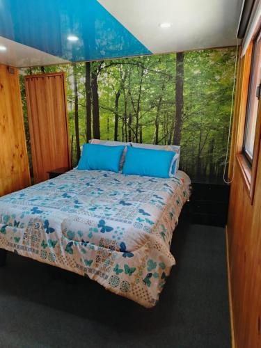 a bed in the middle of a room with trees at Hospedaje Sandra in Llanquihue