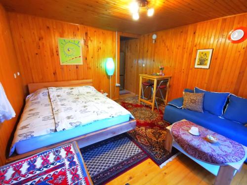 a bedroom with a bed and a couch and a table at MERIKOTKA - a cozy wooden cottage, sLOVEnia in Braslovče