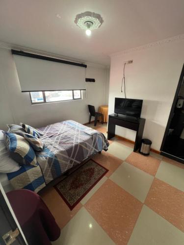 a bedroom with a bed and a table and a piano at Hotel El paraiso Funza in Funza