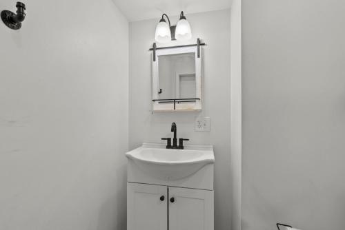a white bathroom with a sink and a mirror at Mint Julep - Studio in Downtown Lexington in Lexington