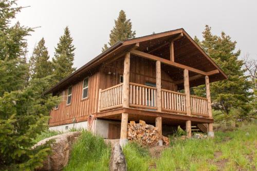 a cabin in the woods with a wrap around deck at Homestake Lodge in Whitehall