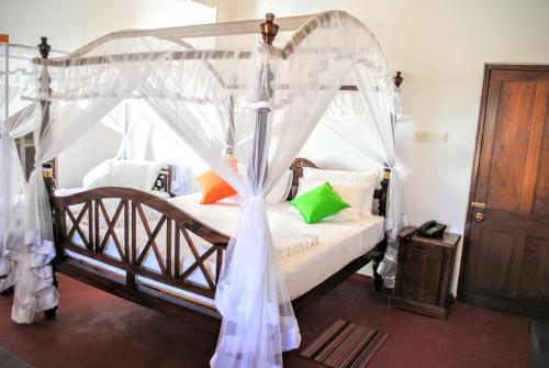a bedroom with a canopy bed with white curtains at Miura Dutch Edge Hotel in Negombo