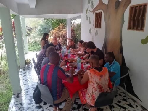 a group of people sitting around a long table at Contany Counda in Abémé