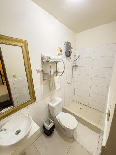 a white bathroom with a toilet and a sink at Hospedaje Gran Imperial in Tumbes