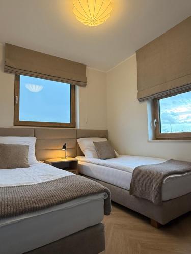 a bedroom with two beds and a large window at Miło in Lubiatowo