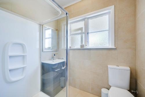 a bathroom with a shower and a toilet and a window at Bird and Fish - Napier Holiday Home in Napier