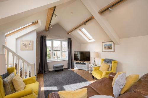 a living room with yellow chairs and a tv at Tanyard Barn - North Yorkshire in York