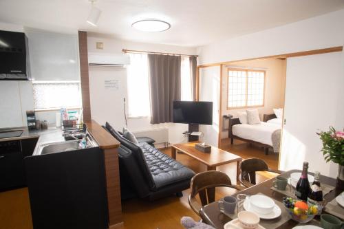 a kitchen and living room with a couch and a table at Guest House Nishimiyanosawa in Teine