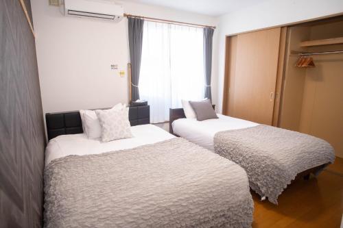 two beds in a small room with a window at Guest House Nishimiyanosawa in Teine