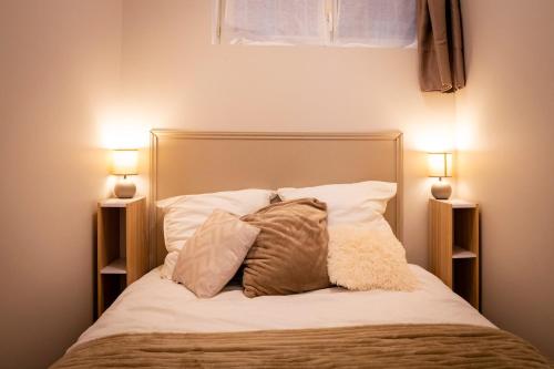 a bed with two pillows and two lights on it at Cocon coloré - centre de Caen - tout à pied in Caen