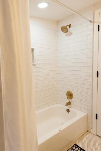 a white bath tub with a shower curtain in a bathroom at Seabiscuit Loft - Studio in Downtown Lexington in Lexington
