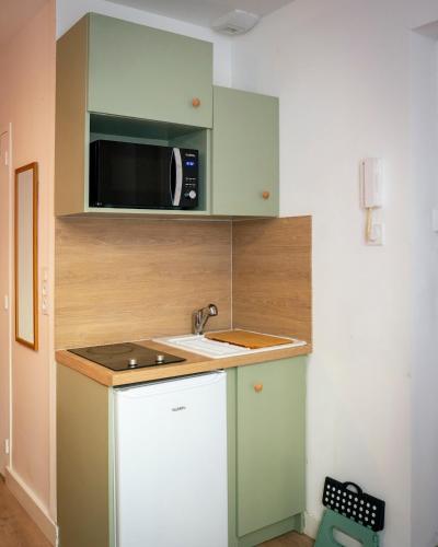 a small kitchen with a microwave and a sink at Cocon coloré - centre de Caen - tout à pied in Caen