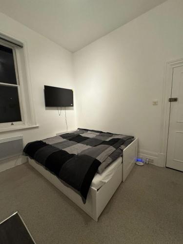 a bedroom with a black and white bed and a window at Self Contained Studio Flat in London