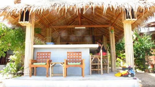 two chairs and a table in front of a hut at Bangpo Village in Ban Bang Po