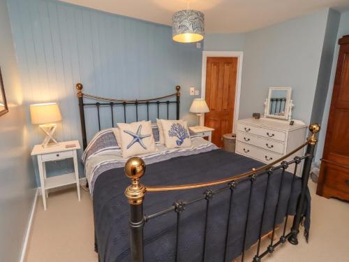 a bedroom with a large bed with blue walls at Corner Cottage in Seahouses