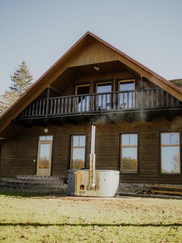 a large wooden house with a balcony on top at Viesu nams Smēdes in Limbaži