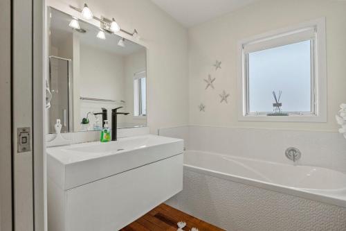 a white bathroom with a sink and a tub and a window at Bliss on Third in Whangarei
