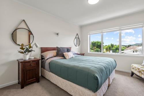 a bedroom with a bed and a mirror and a window at Bliss on Third in Whangarei