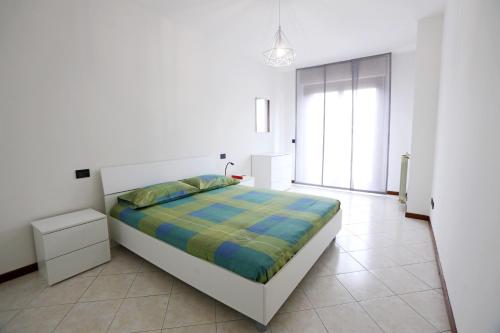 a white bedroom with a bed with a blue and green blanket at Armanni's House in Orio al Serio