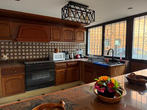 a kitchen with wooden cabinets and a table with a bowl of flowers at Casa Coyoacan in Mexico City