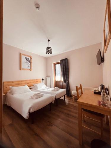 a bedroom with two beds and a desk and a table at Hotel Piccolo Chalet in Claviere