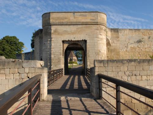 an entrance to a brick wall with a bridge at Hôtel Des Quatrans in Caen