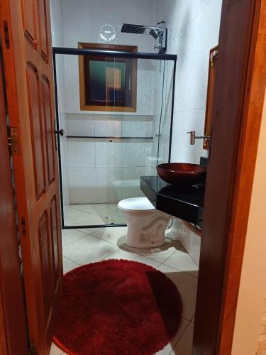 a bathroom with a toilet and a glass shower at Chalés Maktub 1 in Camanducaia
