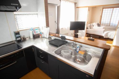 a kitchen with a sink and a living room at Guest House Nishimiyanosawa in Teine