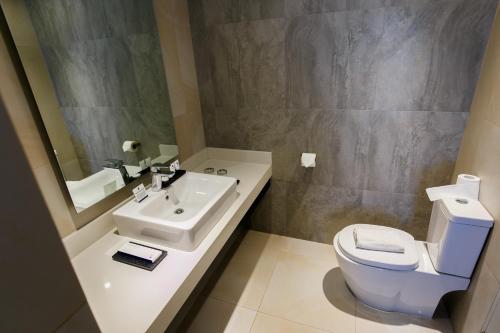 a bathroom with a sink and a toilet and a mirror at Solea Mactan Resort in Mactan