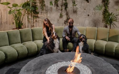 a couple and two dogs sitting next to a fire pit at Volga, Member of Preferred Hotels & Resorts in Mexico City
