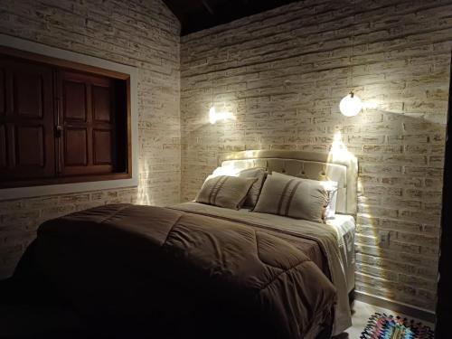 a bedroom with a bed with a brick wall at Chalés Maktub 1 in Camanducaia