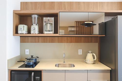 a small kitchen with a sink and a microwave at Jurerê Sol&Mar Temporada in Florianópolis