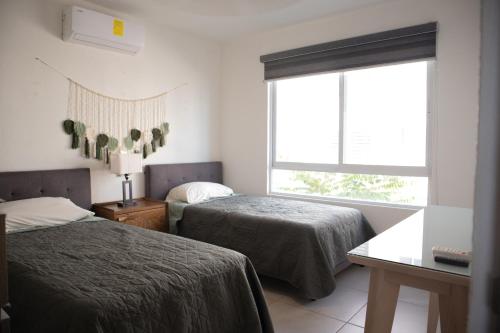 a bedroom with two beds and a window at Escapada familiar, departamento para 8 con Club de Playa incluido in Acapulco