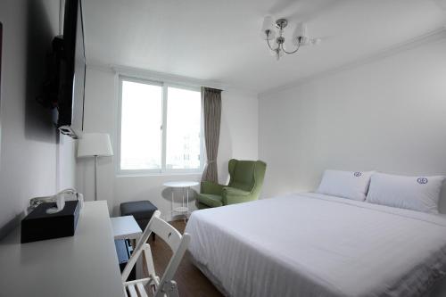 a white bedroom with a bed and a window at Hillside Hotel in Busan