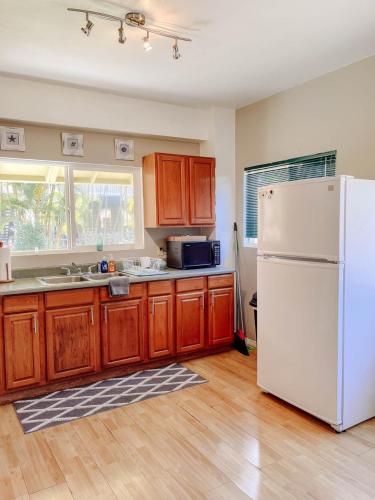 a kitchen with a white refrigerator and wooden cabinets at North Shore Bungalow in Mokuleia