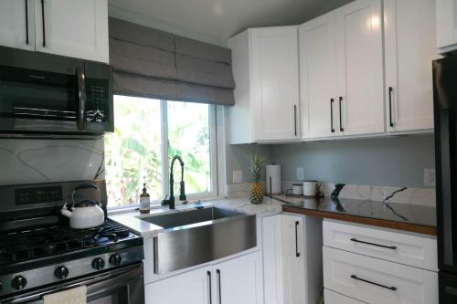 a kitchen with white cabinets and a sink and a stove at North Shore Palms in Mokuleia
