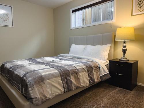 a bedroom with a bed with a lamp and a window at Spacious 4BR with King Suite - Garage - Netflix in Lloydminster