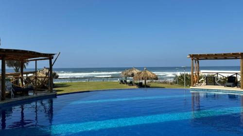 a swimming pool with the beach in the background at Escapada familiar, departamento para 8 con Club de Playa incluido in Acapulco