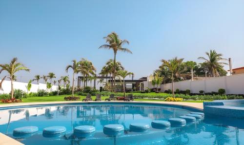 a swimming pool at a resort with palm trees at Escapada familiar, departamento para 8 con Club de Playa incluido in Acapulco