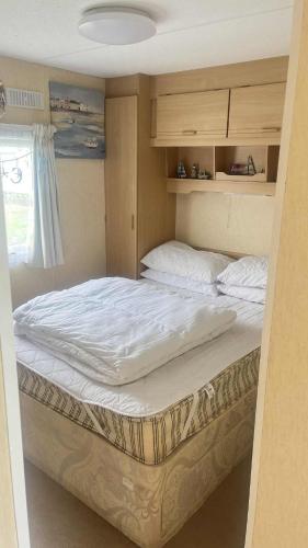 a bedroom with a large bed with white sheets at 10 Berth Caravan - Meadow View in Skegness