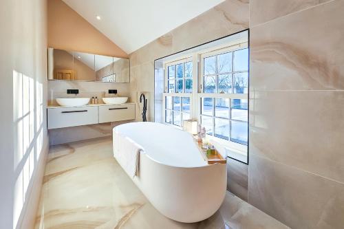 a bathroom with a tub and two sinks and a window at Wayside Farm in Staveley