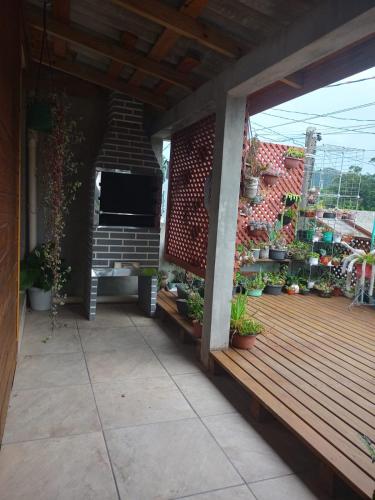 an outdoor deck with potted plants and a grill at Casa Flores do Campo in Florianópolis