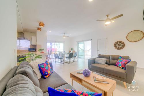 a living room with a couch and a table at Walk to 5th Ave & Beach - Pools, Balcony & Parking in Playa del Carmen