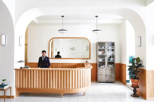 a man in a suit standing behind a counter in a salon at Tilden Hotel Union Square in San Francisco