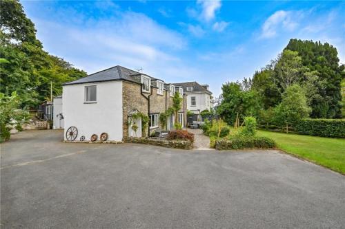 a large white house with a driveway at Wykeham Coach House in Looe