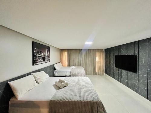 a hotel room with two beds and a flat screen tv at Cabo Branco - Fortune in Tambaú