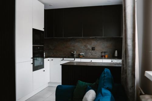 a kitchen with black cabinets and a blue couch at Apartament Patka Wysoki STANDARD in Grudziądz