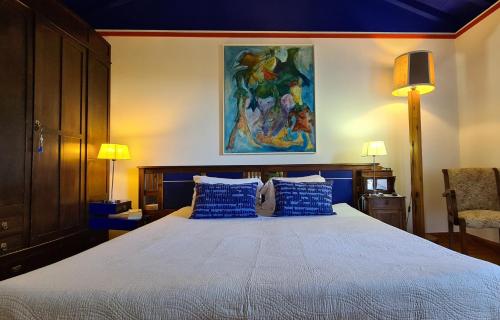 a bedroom with a large bed with blue pillows at Quinta da Meia Eira in Horta