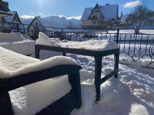 a bench covered in snow next to a fence at Domek Zakopane Folk Chalet in Zakopane
